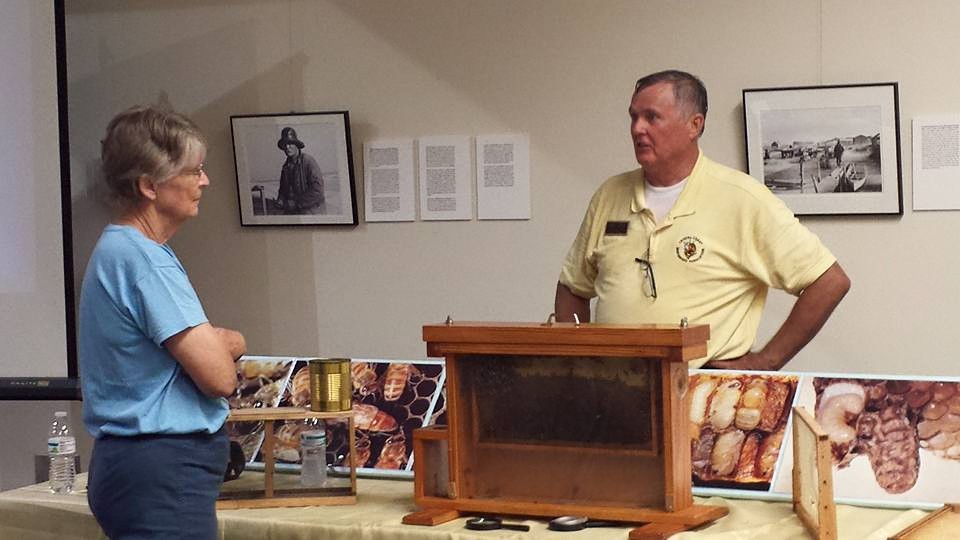 Beekeeper Randall Russell Lewis, right, shares his knowledge of current honey making