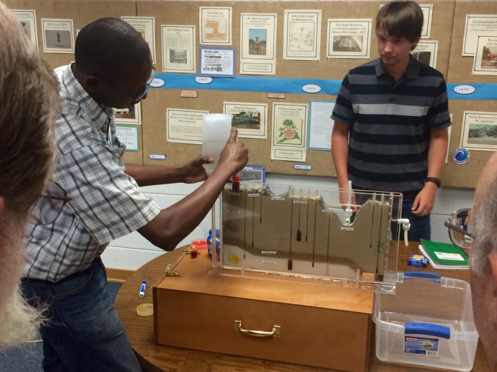 Contamination demo: Alex Manda, left, and research assistant James Owers use a model to demonstrate how contamination plumes, represented here by red- and yellow-colored dye, travel underground. Photo: Mark Hibbs