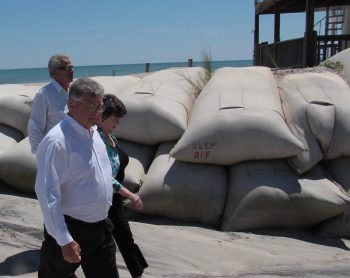Reps. John Torbett, Pat Hurley and Phil Shepard walk past a sandbag wall during a recent legislative tour of North Topsail Beach to see the erosion problems. Photo: Kirk Ross