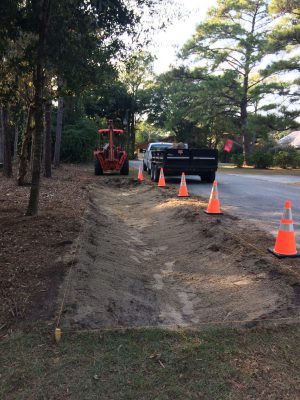 Public works employees at Pine Knoll Shores dig swales on the side of a road. Photo: Bree Tillett